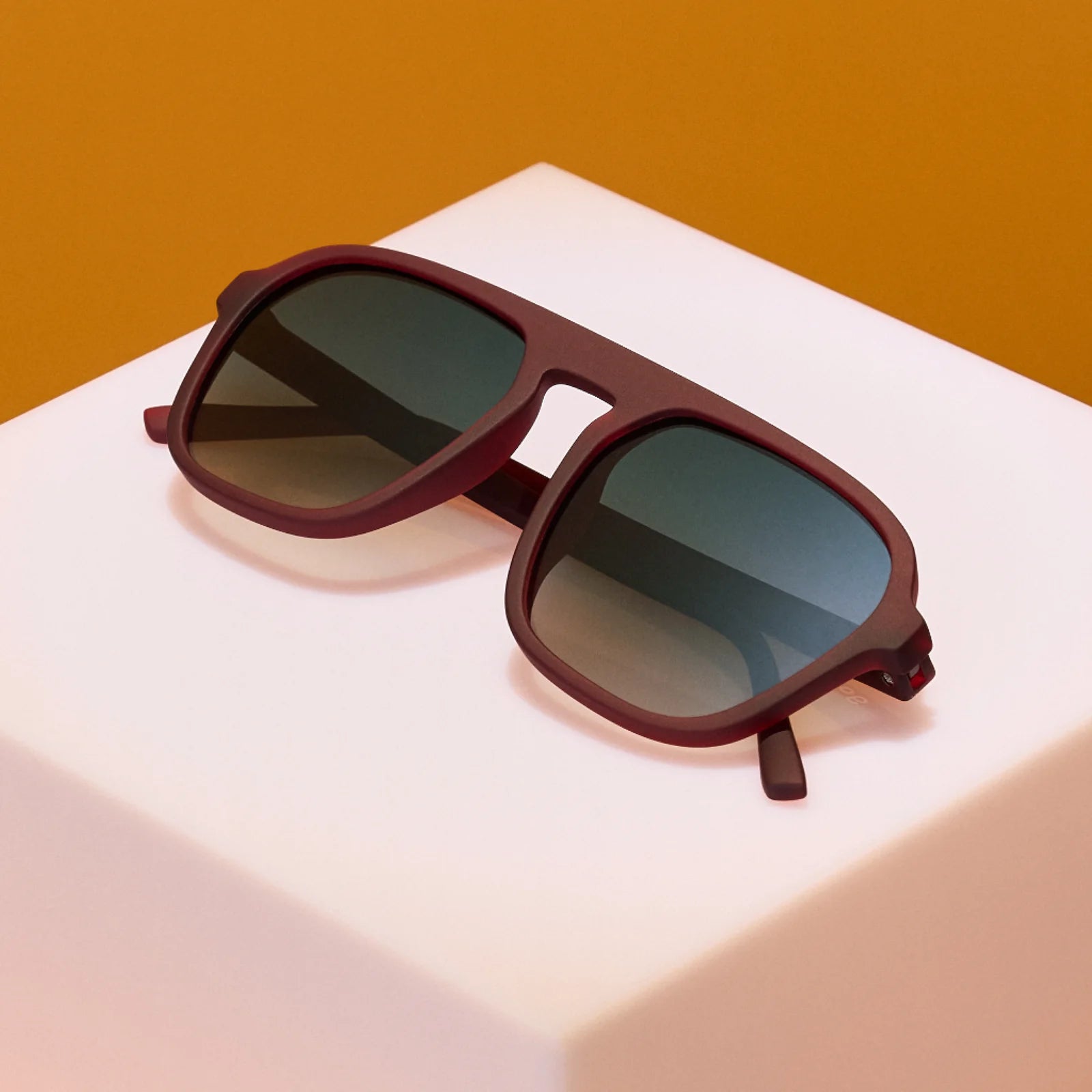 Product close up of brown aviator style sunglasses with green gradient lenses.