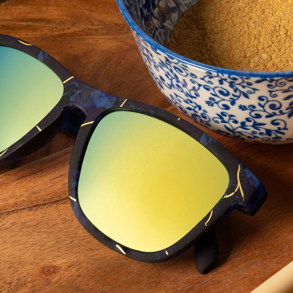 Multi-coloured square-shaped sunglasses with teal-coloured mirrored lenses. 